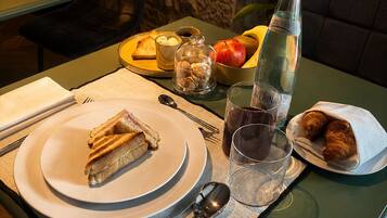 A table set with plates, cutlery, a bottle, and a bowl of fruit.