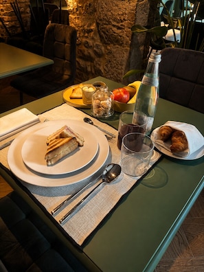 A table set with plates, cutlery, a bottle, and a bowl of fruit.