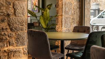 Un comedor con paredes de piedra, una mesa redonda y cuatro sillas, una lámpara colgante y un ventanal grande.