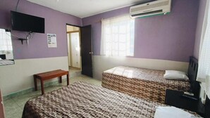A room with two beds, a TV, an air conditioner, and a window with curtains. - Casa Fovissste 1 (Linares)