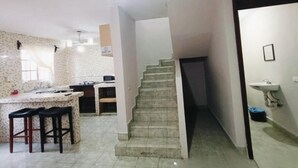 A kitchen with a central island, a staircase, and a sink. - Casa Fovissste 1 (Linares)