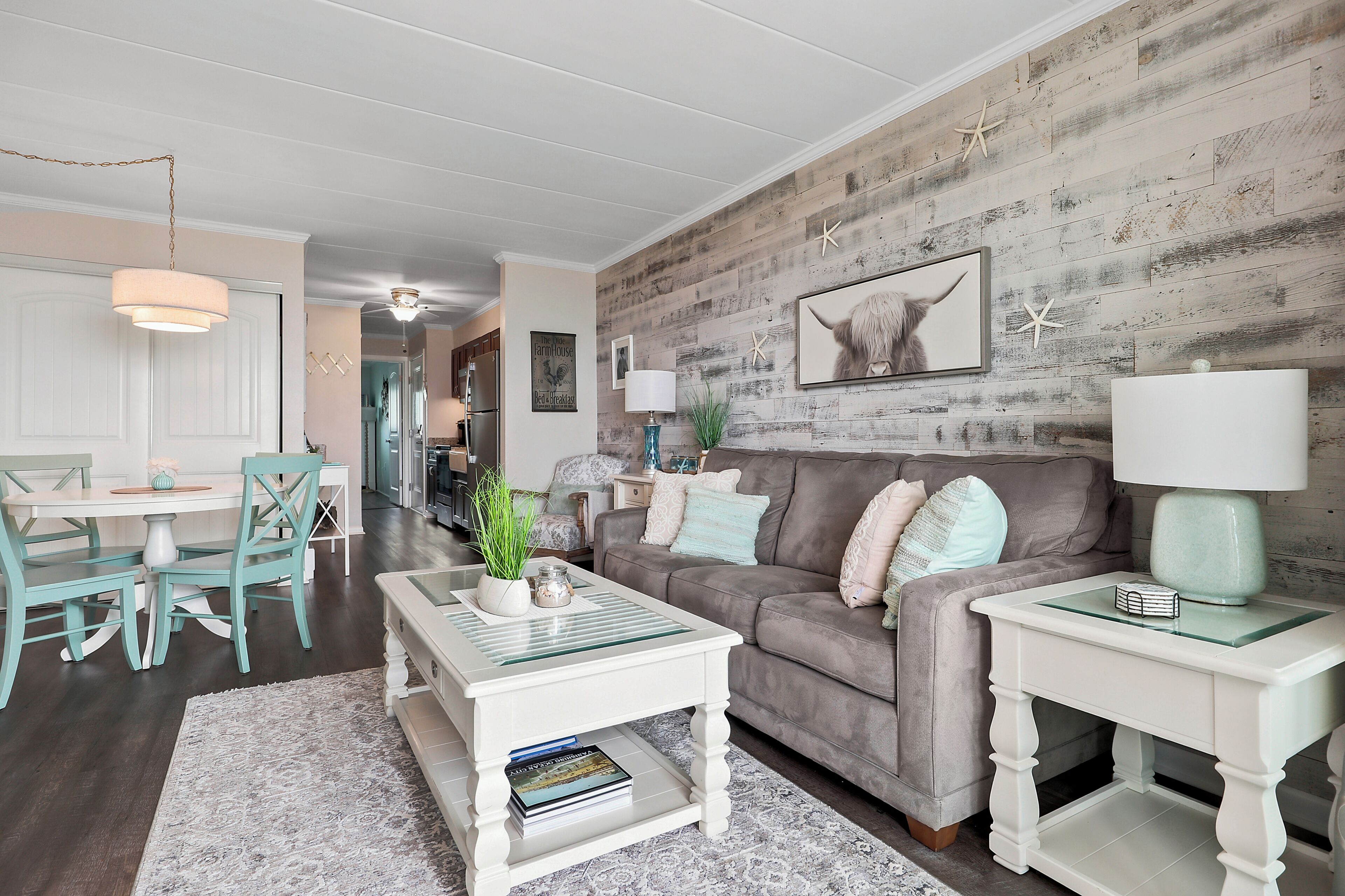 A living room with a wooden wall, a grey sofa, a white coffee table, and a white side table.