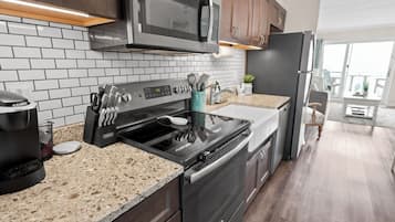 A modern kitchen with stainless steel appliances, a granite countertop, and a white tiled backsplash.