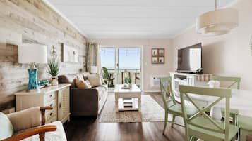 A living room with a sofa, coffee table, and dining area with chairs.