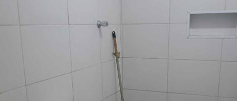 A bathroom with a toilet, sink, and a mop leaning against the wall.