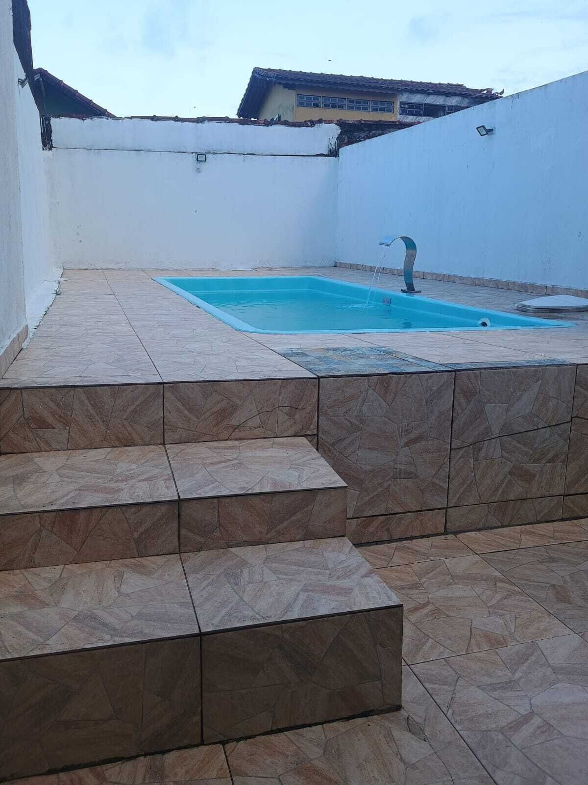 Una piscina en la azotea con una fuente de agua, rodeada de baldosas de piedra y paredes blancas.