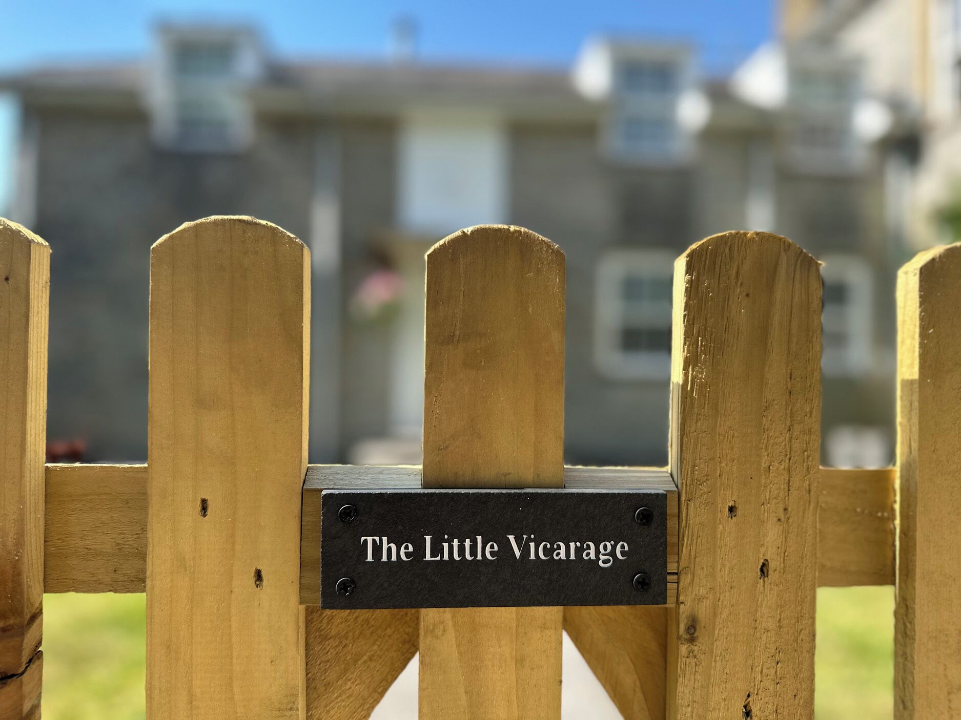 A wooden gate with a sign that reads 'The Little Vicarage.'