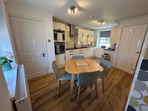 A compact kitchen with a dining table and chairs, white cabinets, and a window.