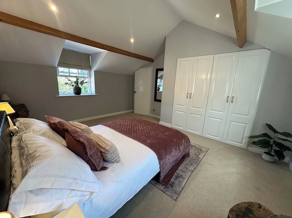 A bedroom with a bed, a window, a wardrobe, and a plant.