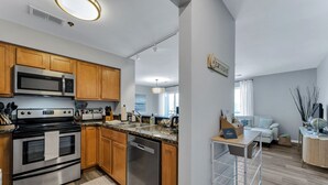 A modern kitchen with stainless steel appliances, wooden cabinets, and a white countertop. - Virginia Beach Condo With Balcony & Pool (Virginia Beach)