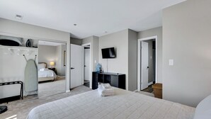 A hotel room with a bed, a TV, a desk, and a wardrobe. - Virginia Beach Condo With Balcony & Pool (Virginia Beach)