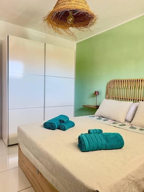 Ein Schlafzimmer mit Bett, Schrank, Nachttisch und einer Pendelleuchte.