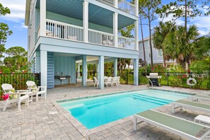 A two-story building with a pool, outdoor seating, and a grill area.