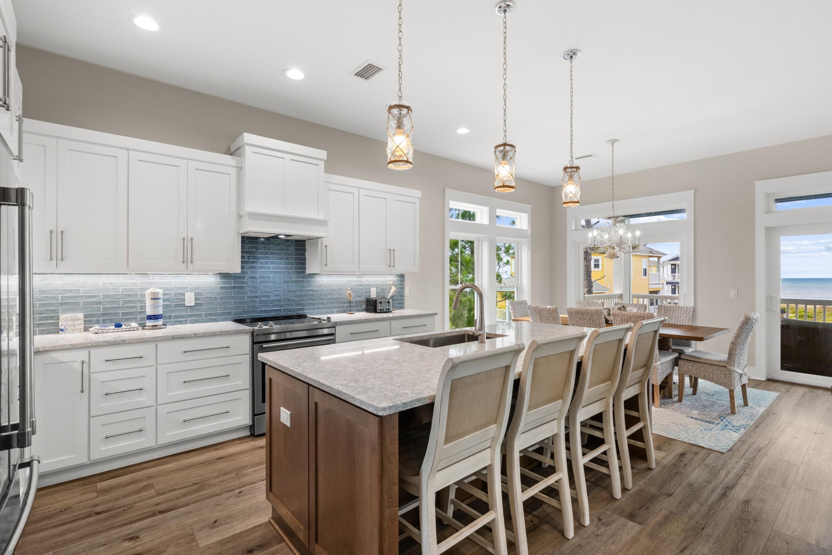 A modern kitchen with white cabinets, a granite countertop, and pendant lighting.