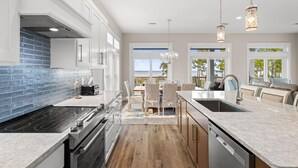 Una cocina moderna con una isla grande, electrodomésticos de acero inoxidable y vistas al exterior.