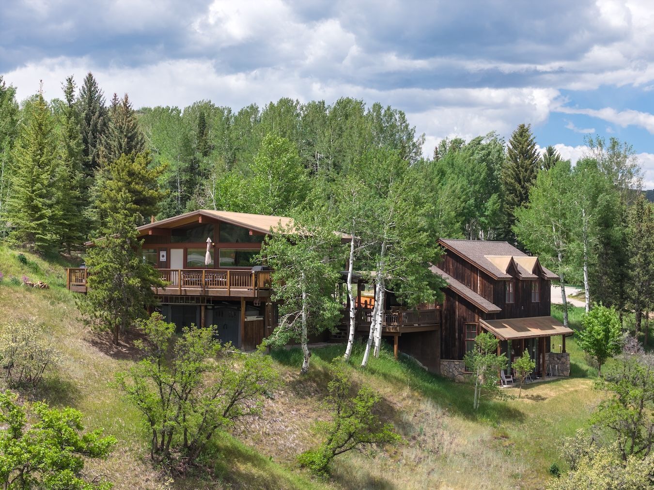 Eine zweistöckige Holzhütte mit Balkon, umgeben von dichtem Wald.