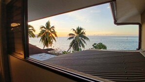A window with a view of the ocean and palm trees.