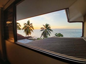 Ein Fenster mit Blick auf das Meer und Palmen.