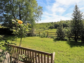 A wooden bench in a grassy area with a view of a hilly landscape and a wooden fence. - Bib Knowl Farm (Rochdale)
