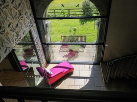 Una habitación con un ventanal amplio, una silla rosa y vistas a un jardín.