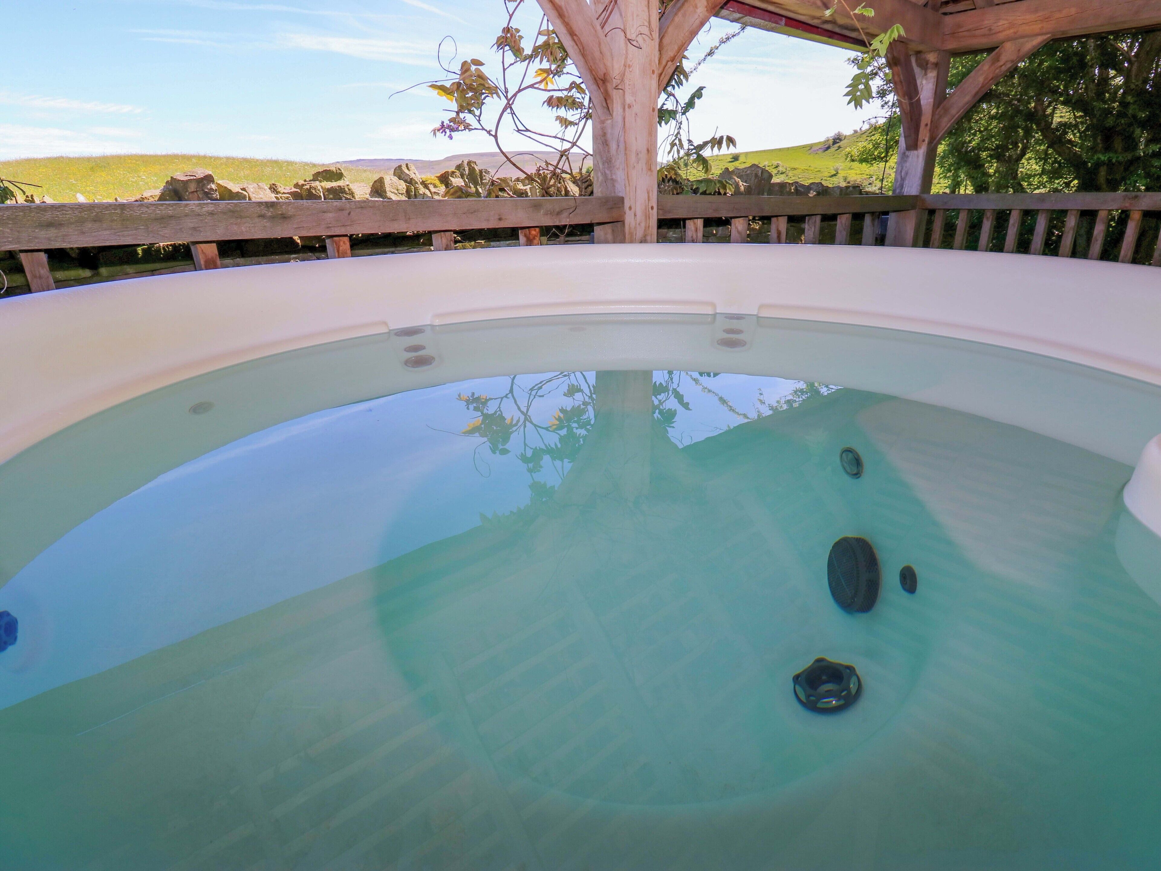 Ein Whirlpool mit einer Holzterrasse und Blick auf eine grüne Landschaft.