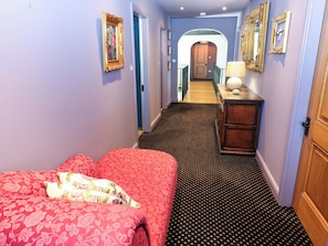 A hotel room with a bed, a dresser, a mirror, and a hallway leading to another room. - Bib Knowl Farm (Rochdale)