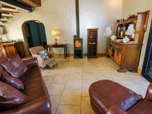 Un salon chaleureux avec une cheminée, des canapés en cuir, un buffet en bois et une table à manger.