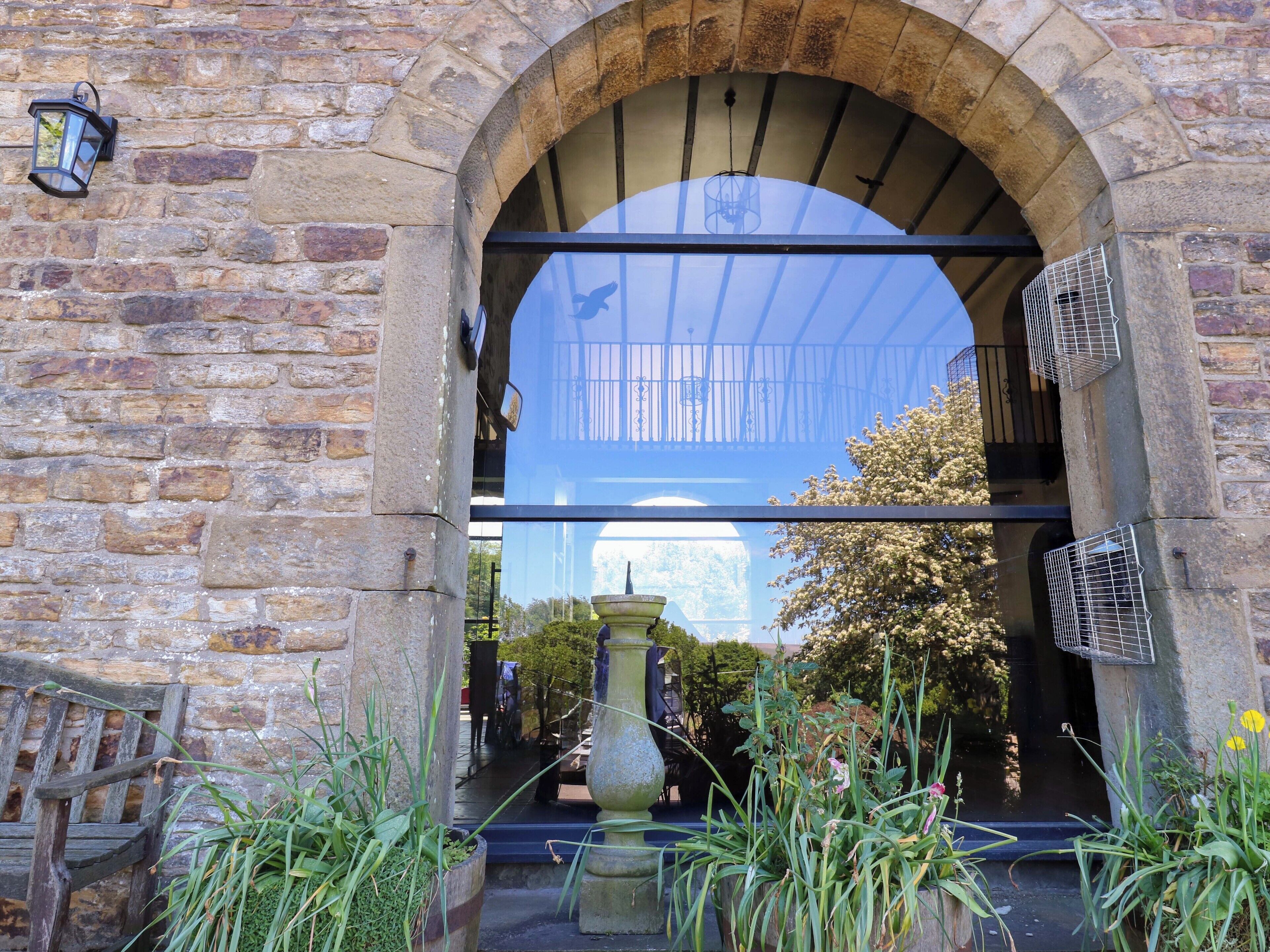 A stone archway with a glass door, a lantern, and a fountain in the foreground.