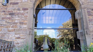 A stone archway with a glass door, a lantern, and a fountain in the foreground.