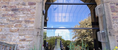 A stone archway with a glass door, a lantern, and a fountain in the foreground.