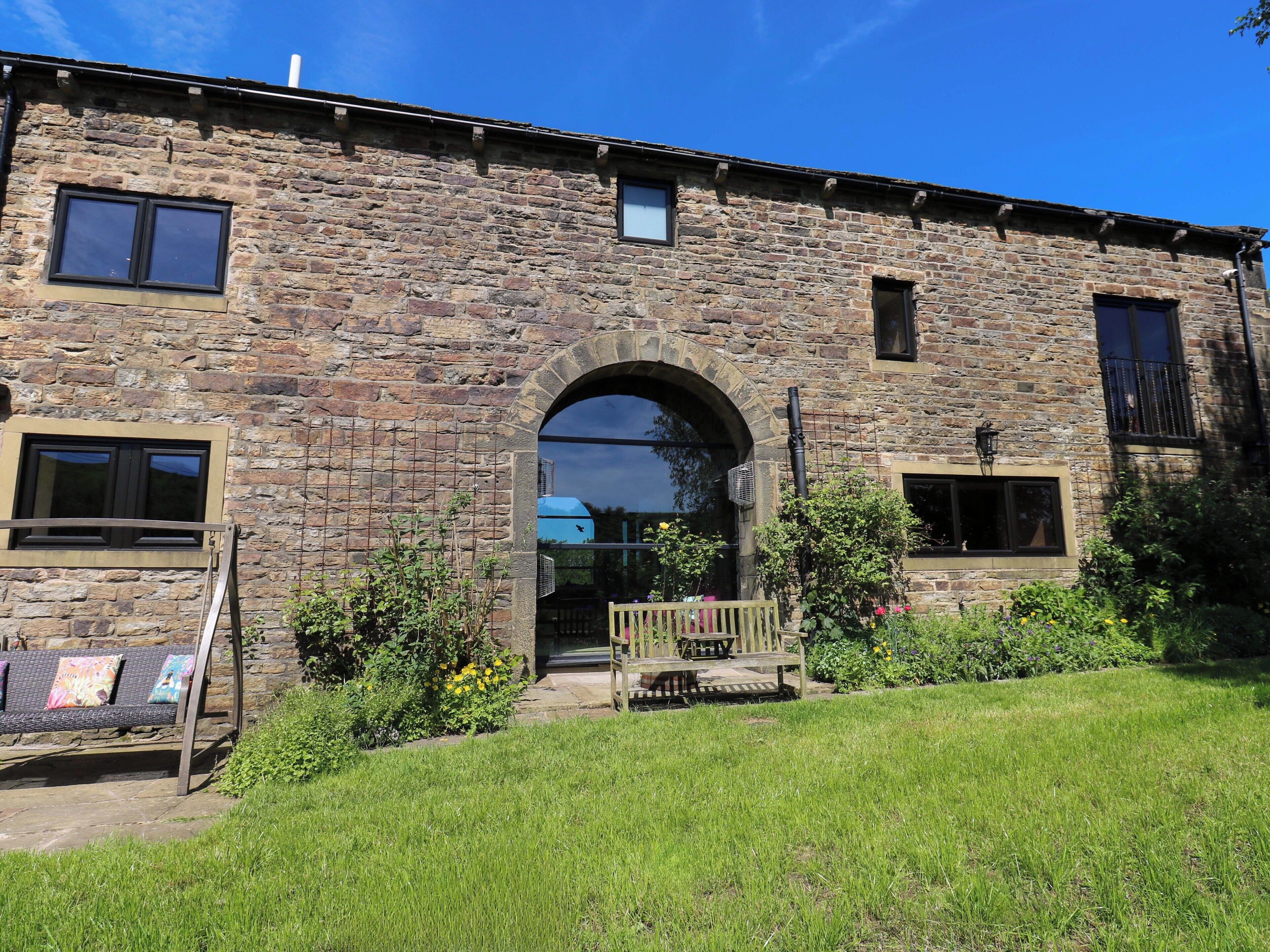 A stone building with a large arched entrance, a small porch, and a grassy lawn.