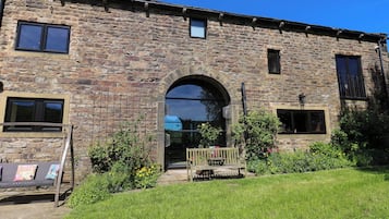 A stone building with a large arched entrance, a small porch, and a grassy lawn.