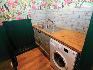 A small kitchen with a washing machine, a sink, and a wooden countertop. - Bib Knowl Farm (Rochdale)