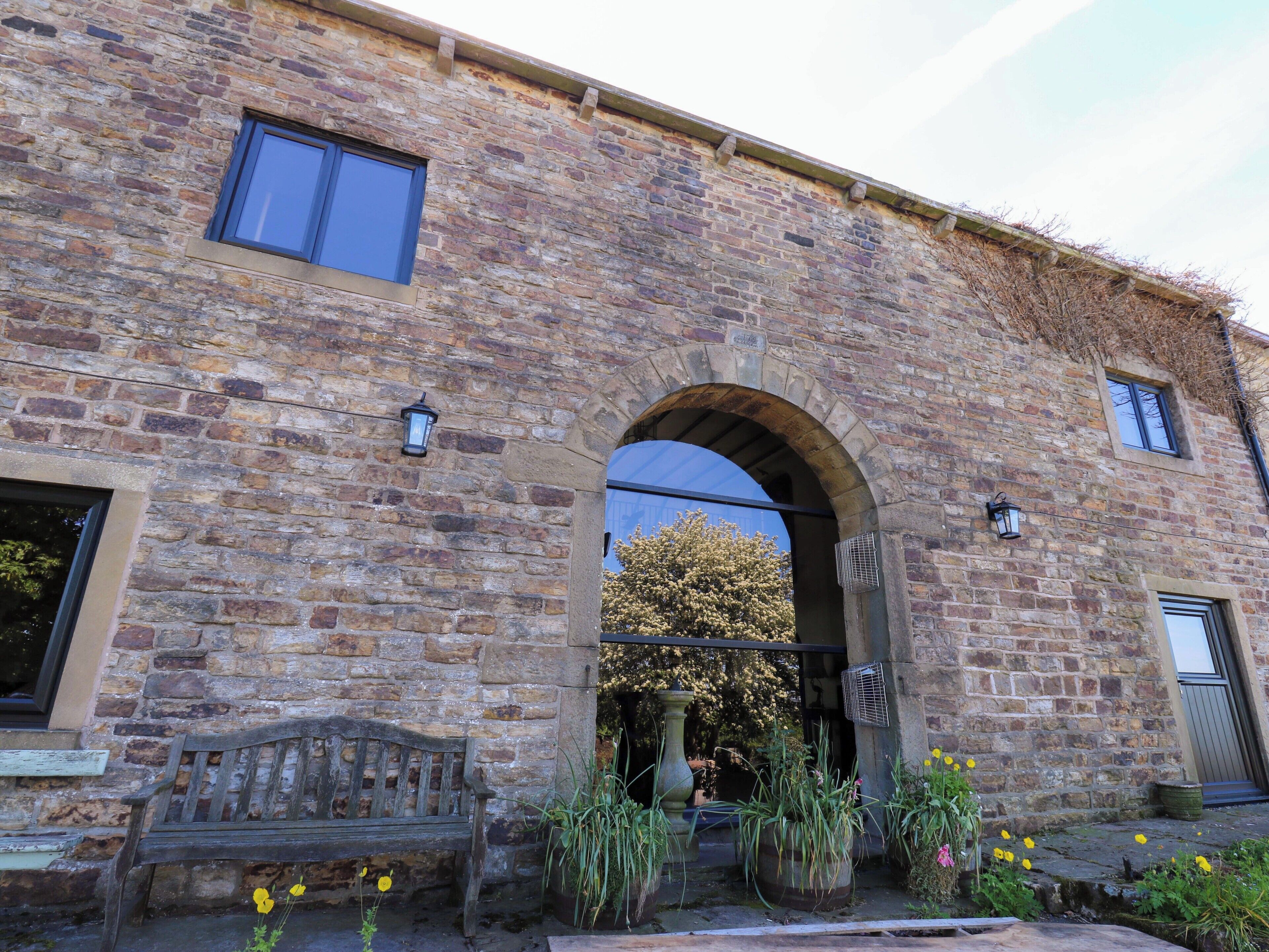 A stone building with an arched entrance, a bench, and potted plants.