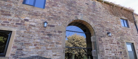 A stone building with an arched entrance, a bench, and potted plants.