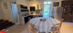 A kitchen with a dining table, chairs, a refrigerator, and a microwave.