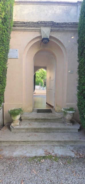 An entrance with an arched doorway, steps leading up to it, and two planters on either side.