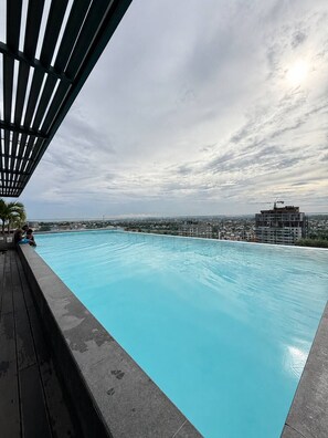 Ein Pool auf dem Dach mit Blick auf eine Stadtlandschaft und einen bewölkten Himmel.