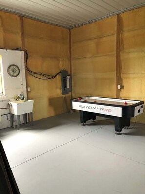 A room with a PlayCraftPro pool table, a sink, and a clock on the wall.