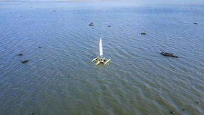 A single-person sailboat on calm water with scattered rocks. - Terra San Miguel Glapming (Flores de Begoña)