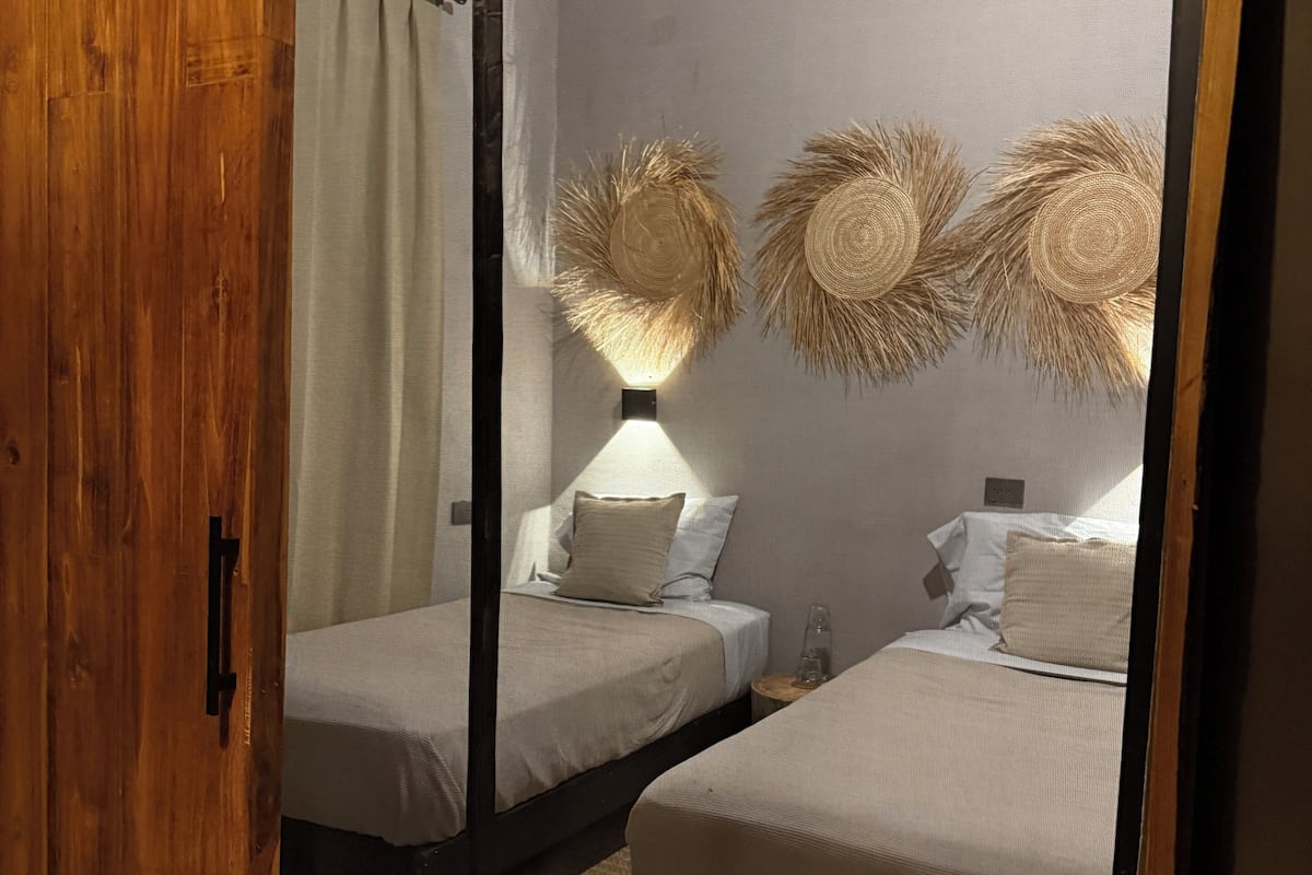Un dormitorio con dos camas, una puerta de madera y un techo con vigas a la vista.