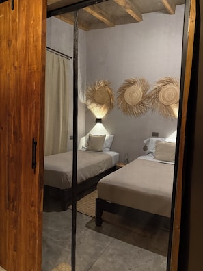 A bedroom with two beds, a wooden door, and a ceiling with exposed beams. - Terra San Miguel Glapming (Flores de Begoña)