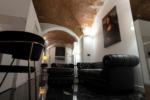 Ein modernes Interieur mit einem schwarzen Ledersofa, einem schwarzen Ohrensessel und einem Marmorboden.