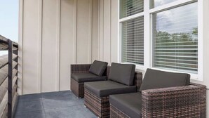 Un patio cubierto con mobiliario de mimbre y vistas al exterior.