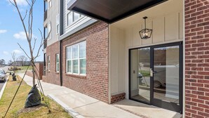 En moderne bygning med murstensfacade, store vinduer og en glasdør.