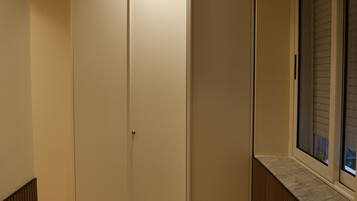 A hallway with a wooden floor, a sliding door, and a window with blinds.