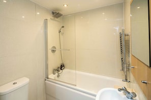 Un baño moderno con ducha envuelta en vidrio, una bañera blanca y un lavabo con espejo.