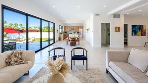 A spacious living area with a large window, a dining area, and a kitchen. - Modern Villa|Palm Desert|Great location|Pool|Spa (Palm Desert)