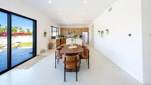 A modern kitchen with wooden cabinets, a central island, and a dining area with a round table and chairs. - Modern Villa|Palm Desert|Great location|Pool|Spa (Palm Desert)