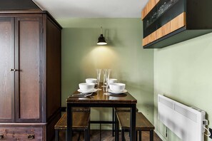 Comedor con mesa dispuesta para cuatro, un armario y un radiador fijado a la pared.